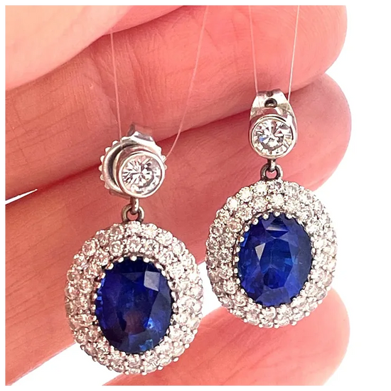 Pair of earrings with blue gemstones held between fingers