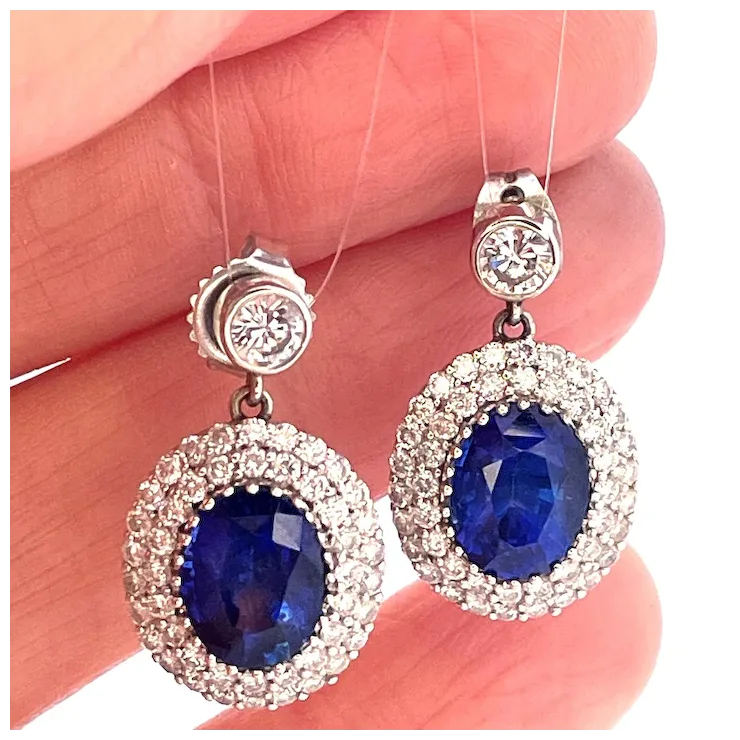 Pair of earrings with blue gemstones held between fingers