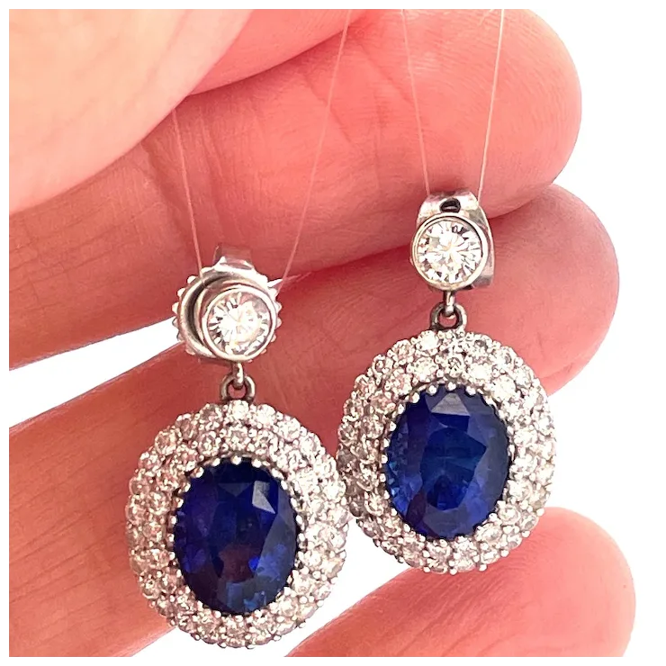 Pair of earrings with blue gemstones held between fingers