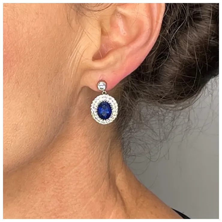 Close-up of an ear wearing a blue gemstone earring with a silver setting.