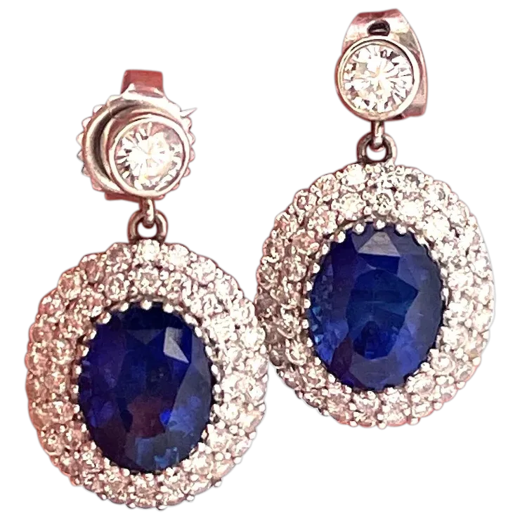 Pair of earrings with blue gemstones and rose gold accents on a white background