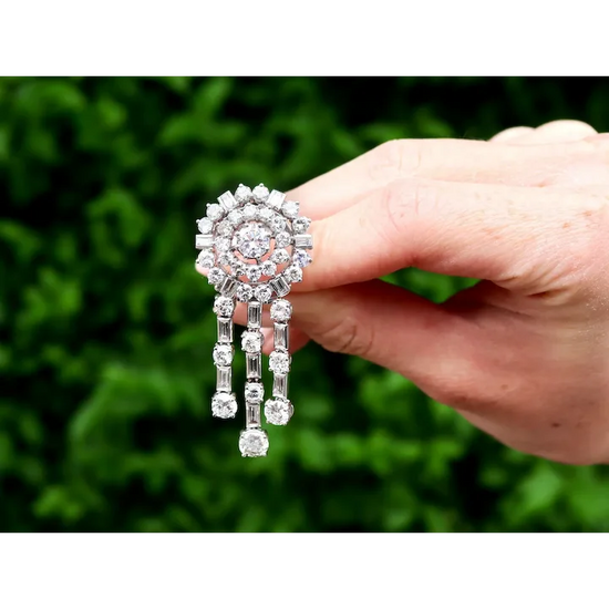 Diamond earring held by a hand against a blurred green background