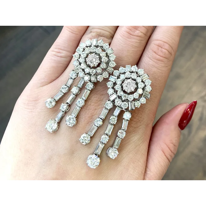 Diamond earrings held in a hand with a blurred background