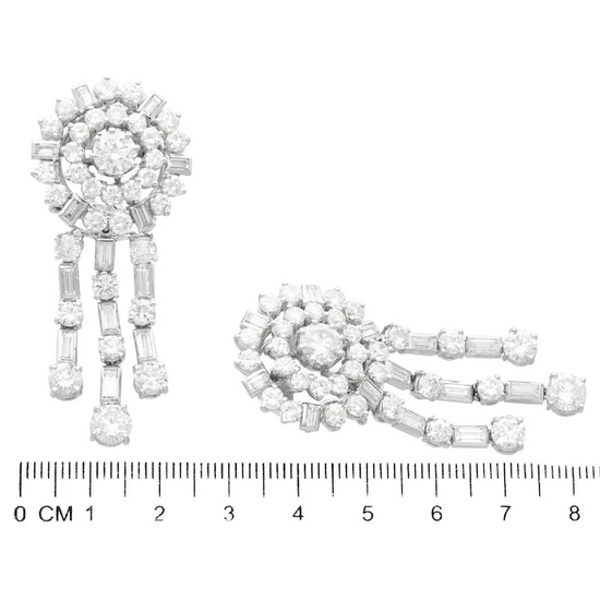 Pair of diamond earrings with a ruler for scale on a white background