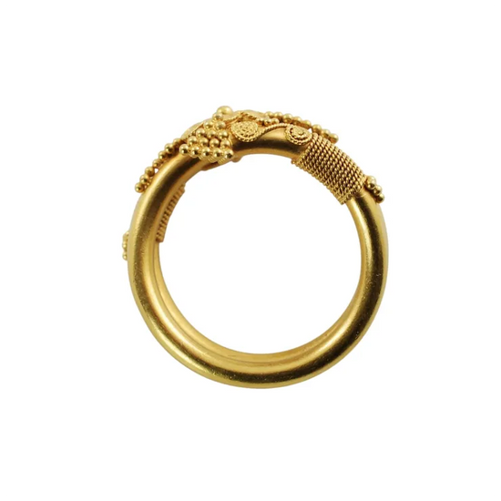 Gold ring with intricate design on a white background