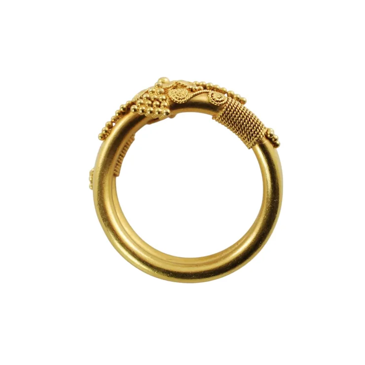 Gold ring with intricate design on a white background