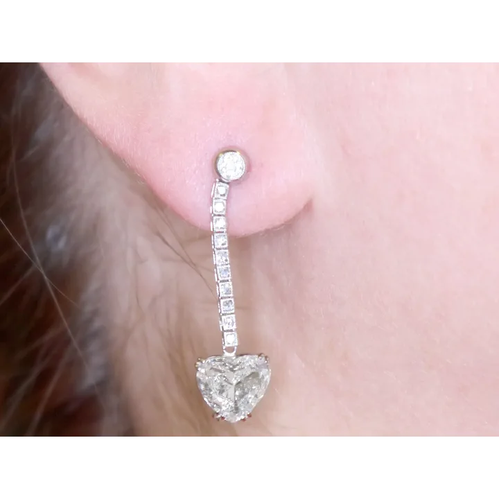 Diamond earring worn on an ear with a plain background