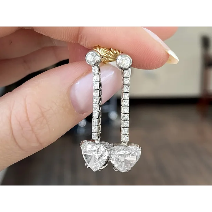 Diamond earrings held between fingers with a blurred background
