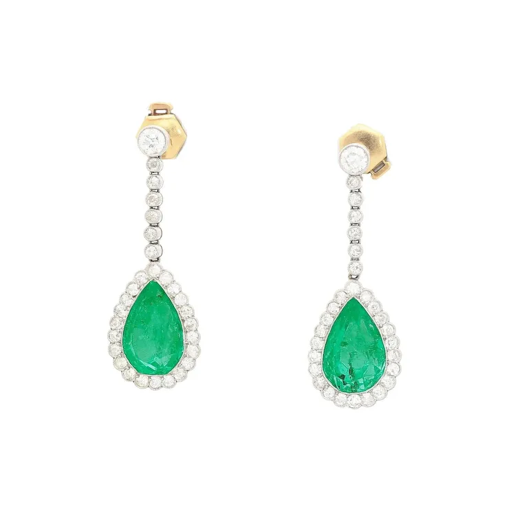 Pair of emerald and diamond earrings on a white background