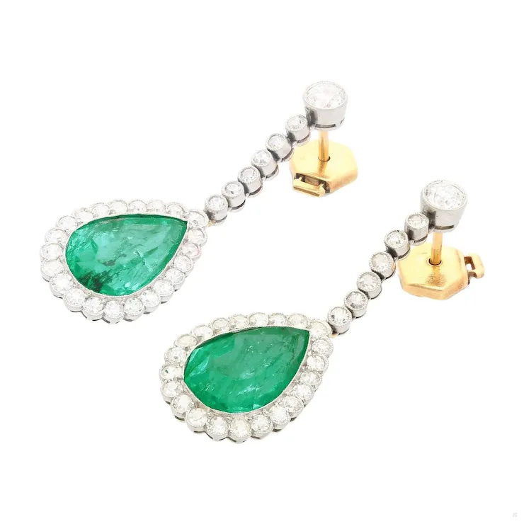 Pair of earrings with green gemstones and gold accents on a white background