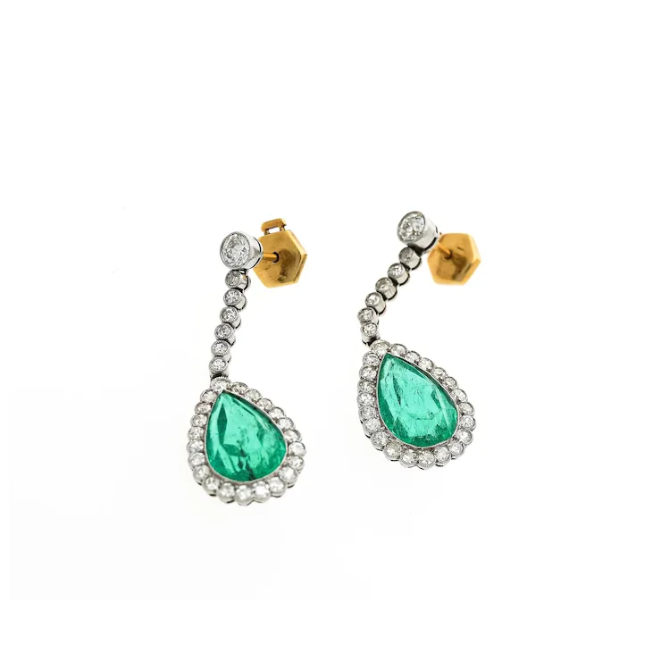 Pair of earrings with green teardrop stones and gold accents on a white background