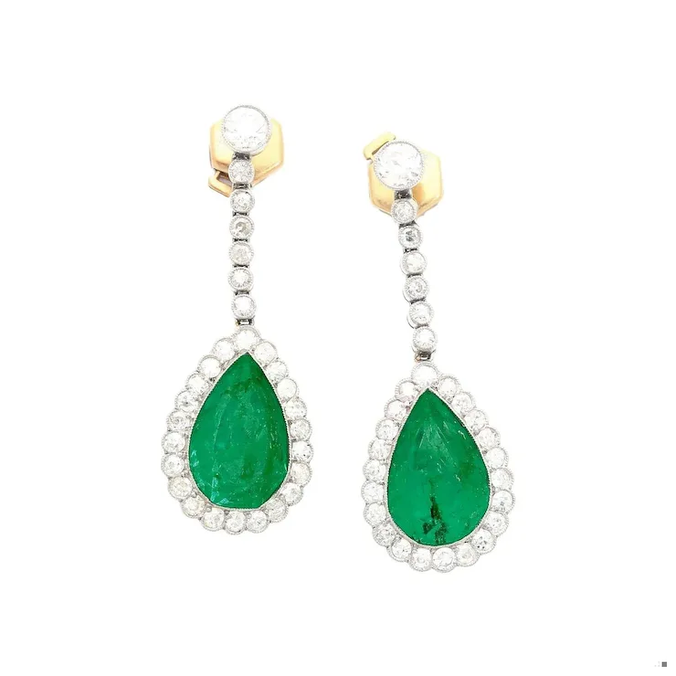 Pair of earrings with green gemstones and gold accents on a white background
