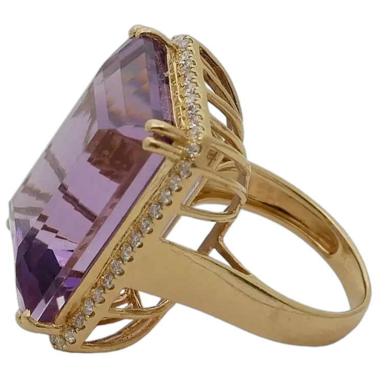 Gold ring with a large purple gemstone and smaller diamonds on a white background