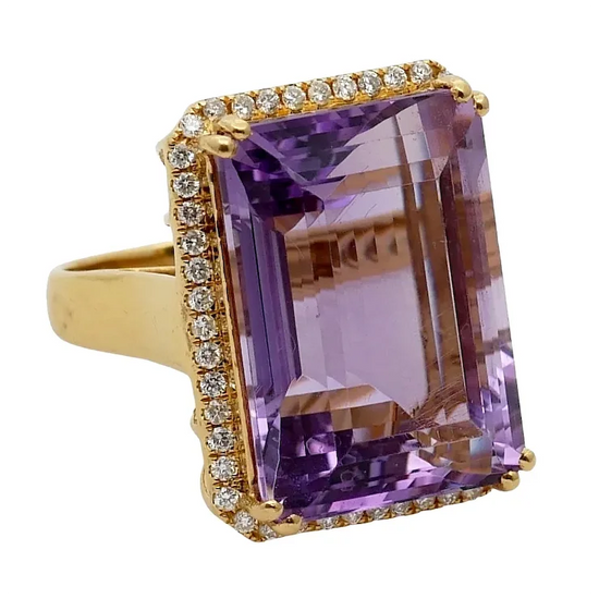 Gold ring with a large purple gemstone and smaller diamonds on a white background