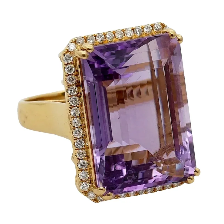 Gold ring with a large purple gemstone and smaller diamonds on a white background