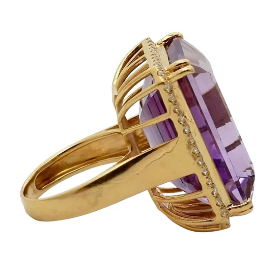 Gold ring with a large purple gemstone on a white background