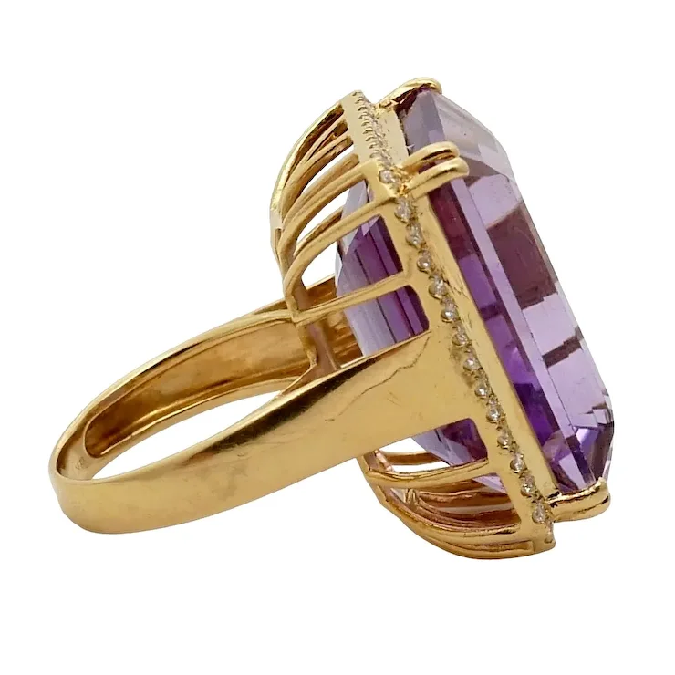 Gold ring with a large purple gemstone on a white background