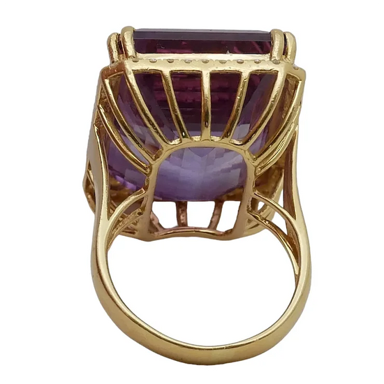 Gold ring with a purple gemstone on a white background