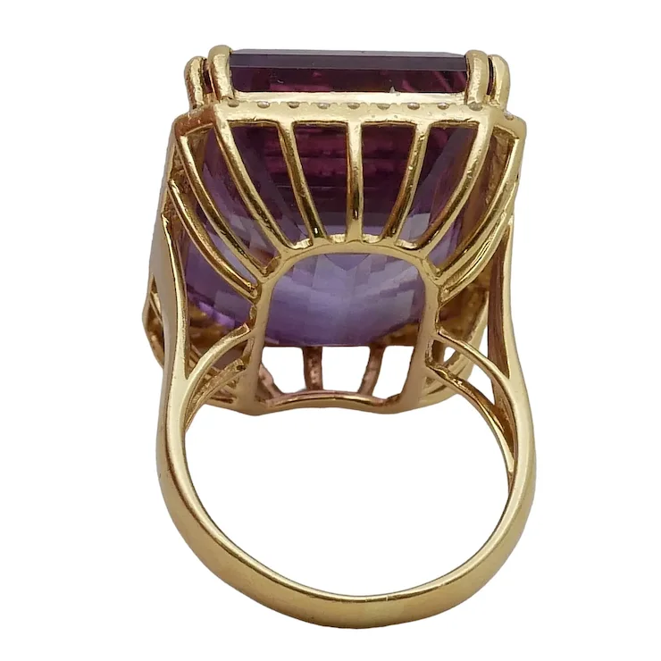 Gold ring with a purple gemstone on a white background