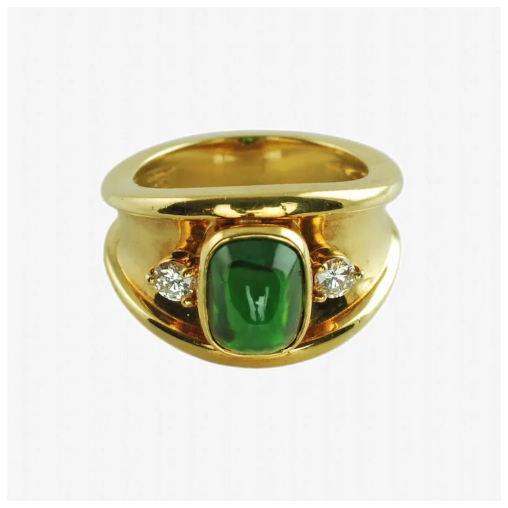 Gold ring with a green gemstone and two diamonds on a white background