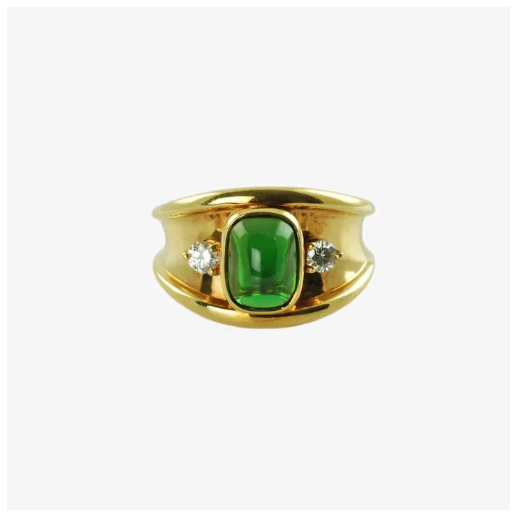 Gold ring with a green gemstone and two diamonds on a white background
