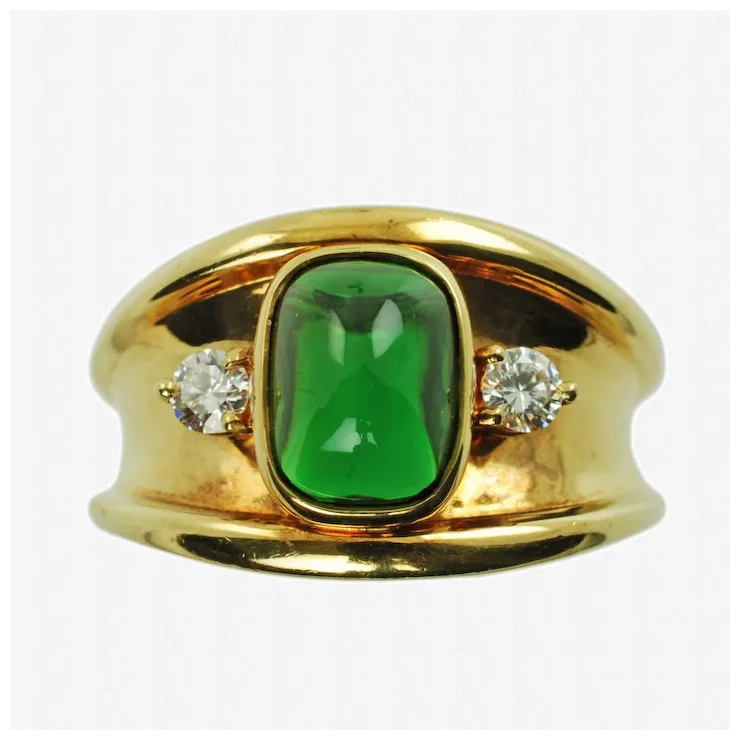 Gold ring with a green gemstone and two diamonds on a white background