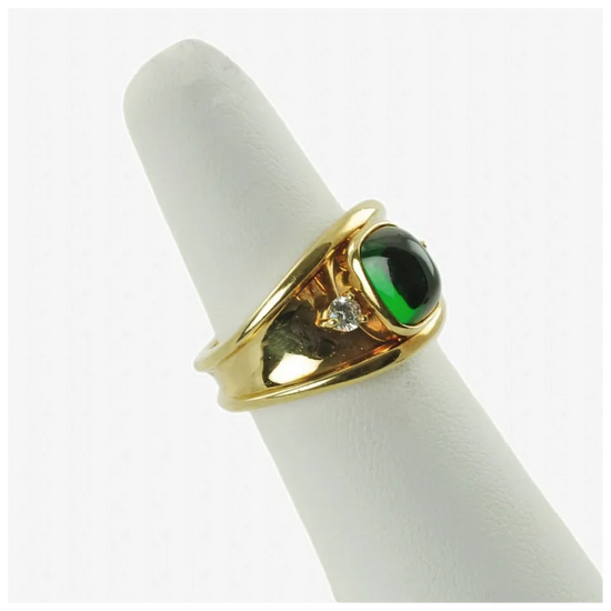 Gold ring with a green gemstone on a white cushion