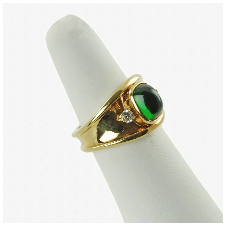 Gold ring with a green gemstone on a white cushion