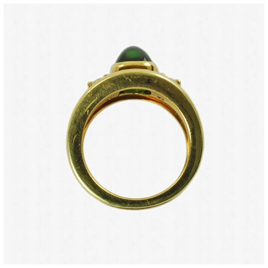 Gold ring with a green gemstone on a white background