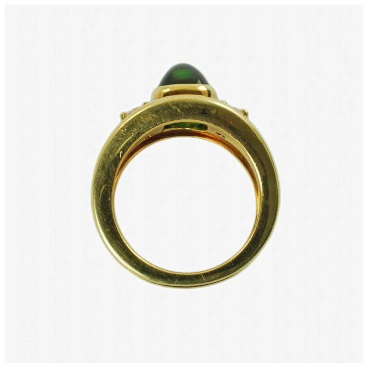 Gold ring with a green gemstone on a white background