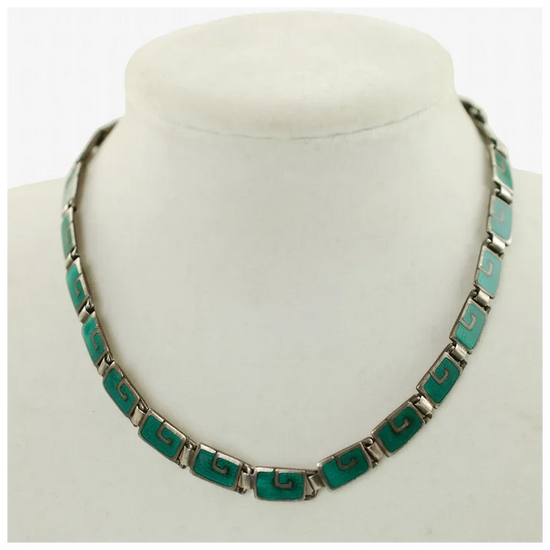 Necklace with green and silver design on a mannequin bust against a white background