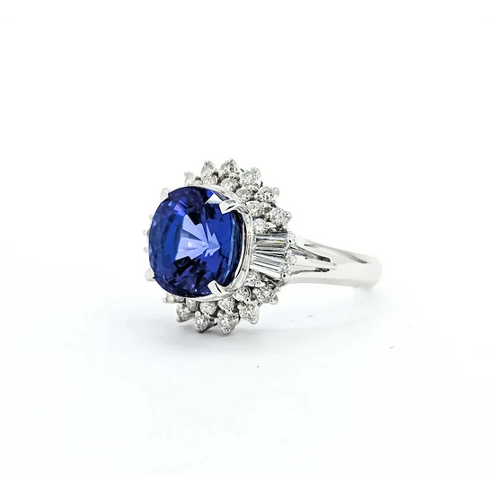 Ring with a blue gemstone and diamond-studded halo on a white background