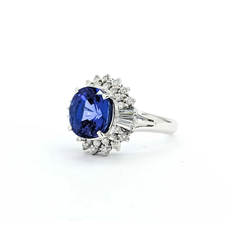 Ring with a blue gemstone and diamond-studded halo on a white background