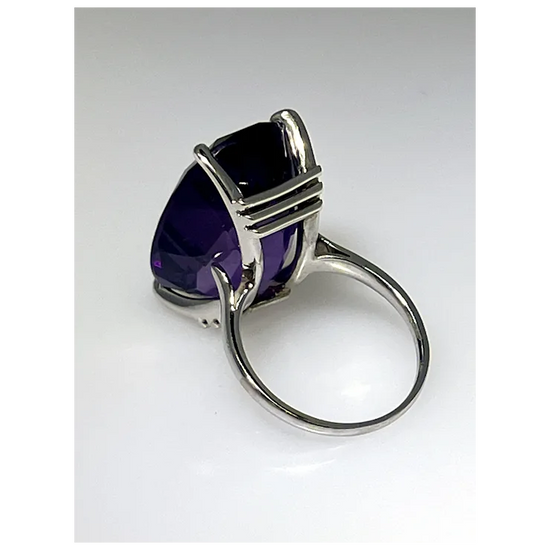 Silver ring with a large purple gemstone on a white background
