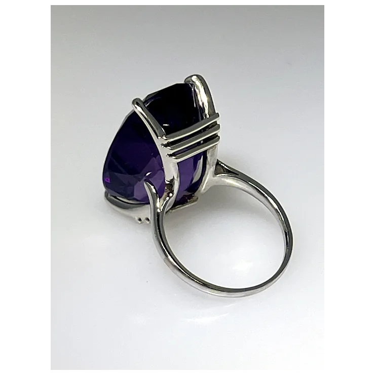 Silver ring with a large purple gemstone on a white background