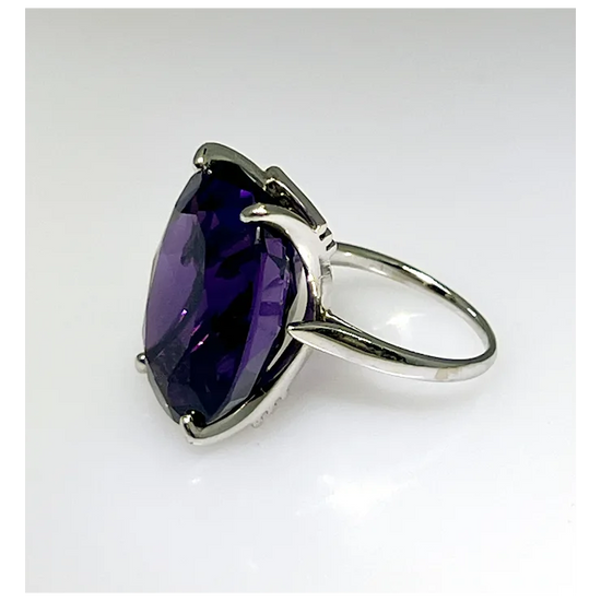 Silver ring with a large purple gemstone on a white background
