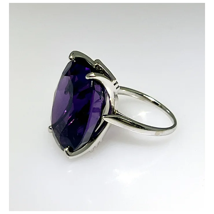 Silver ring with a large purple gemstone on a white background