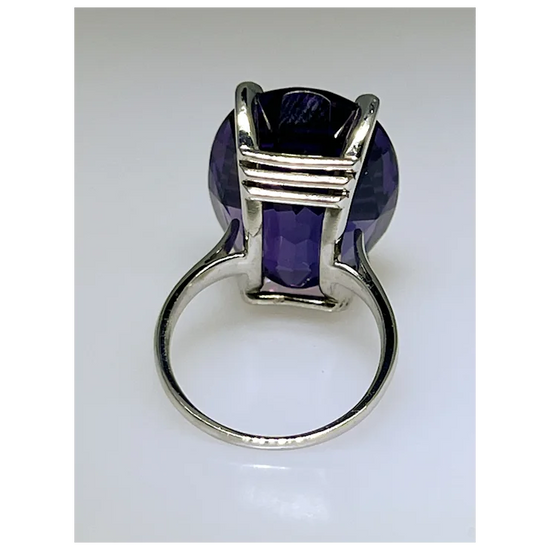 Silver ring with a purple gemstone on a white background