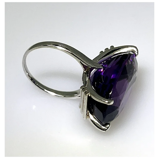 Silver ring with a large purple gemstone on a white background