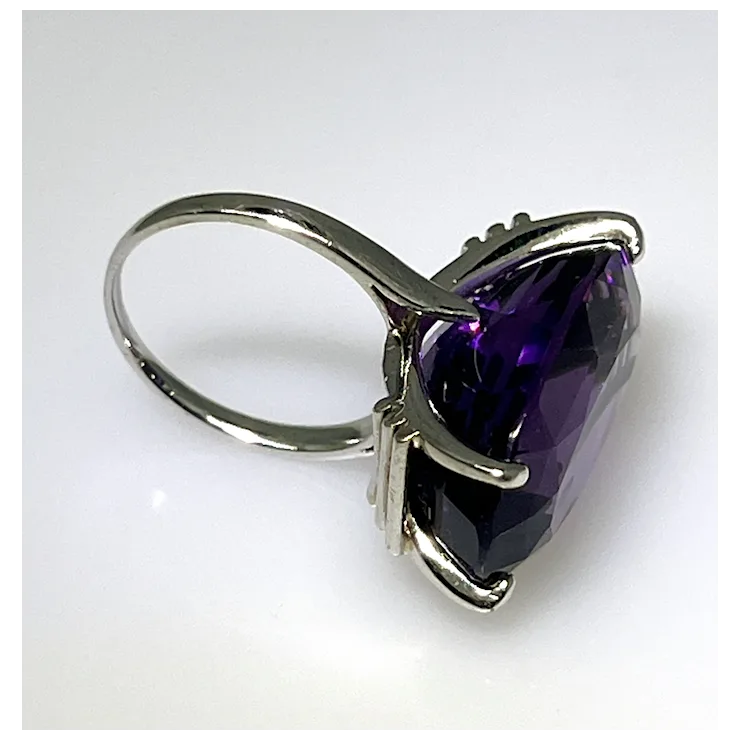 Silver ring with a large purple gemstone on a white background