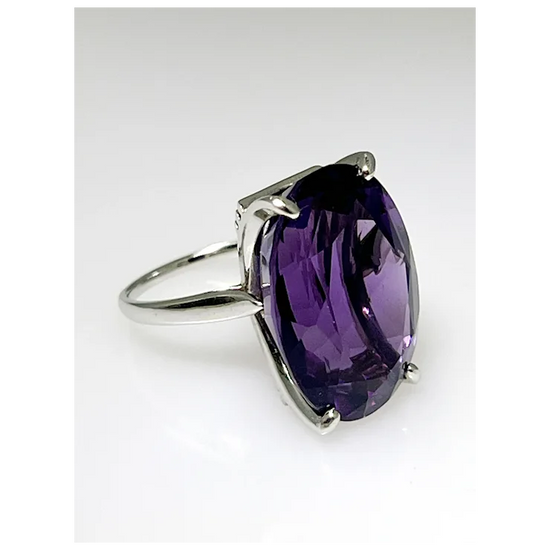 Silver ring with a large purple gemstone on a white background