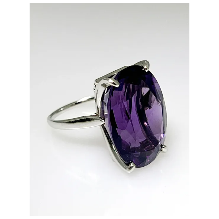 Silver ring with a large purple gemstone on a white background